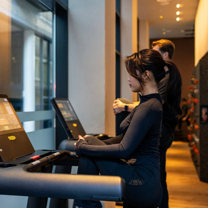 Female client warming up on treadmill with digital display during a personal training session at Fit by David gym in Amsterdam, focused on cardio training, weight loss, and fitness coaching.